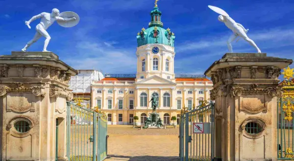 Pałac Charlottenburg w stylu rokoko, z bramą i posągami strażników.